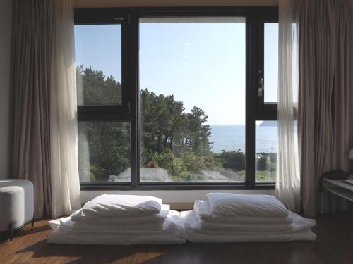 a bedroom with two beds in front of a large window at Hotel Seogwipean in Seogwipo