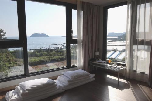 a hotel room with a bed in front of large windows at Hotel Seogwipean in Seogwipo