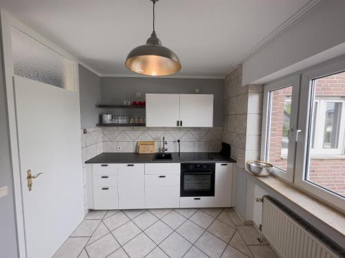 a kitchen with white cabinets and a sink and a window at Ruhiges Juwel: frisch renoviert 100 qm in Jülich