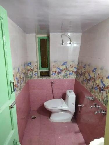 a pink bathroom with a toilet and a mirror at The Moon Light Home stay in Bhīm Tāl