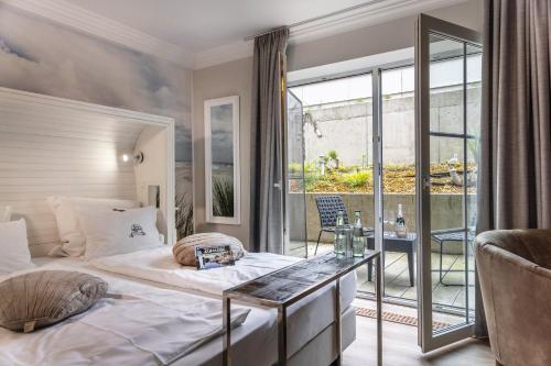 a bedroom with a large bed and a balcony at HOTEL DÜNENLÄUFER Carolinensiel in Carolinensiel