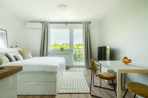 1 dormitorio con cama, escritorio y ventana en Urban & Green Apartments by Ambiente en Prievoz