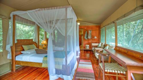 a bedroom with a canopy bed and a desk at Mara Leisure Camp in Talek