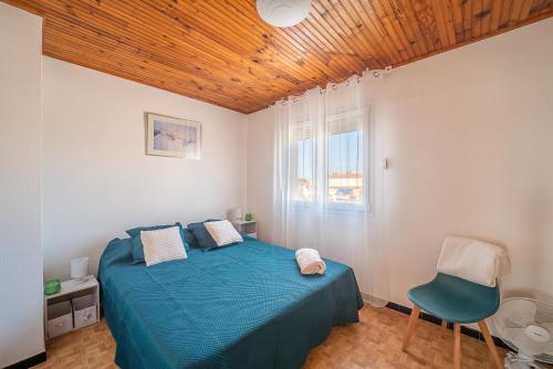 ein Schlafzimmer mit einem blauen Bett und einem Stuhl in der Unterkunft Une Maison à la Mer - Proche de la marina in Saint-Cyprien