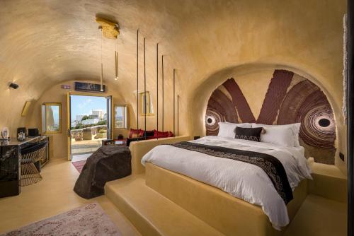una grande camera da letto con un grande letto con soffitto ad arco di Canyon Santorini a Firà