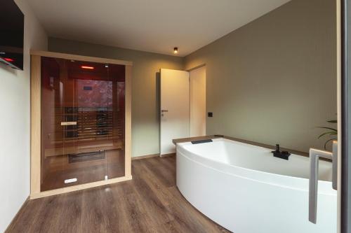 a large bathroom with a tub and a glass door at Hotel Castel Mani in San Lorenzo in Banale