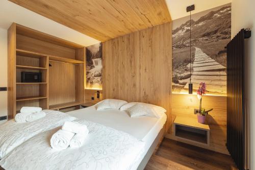 a bedroom with a large white bed with wooden walls at Hotel Castel Mani in San Lorenzo in Banale
