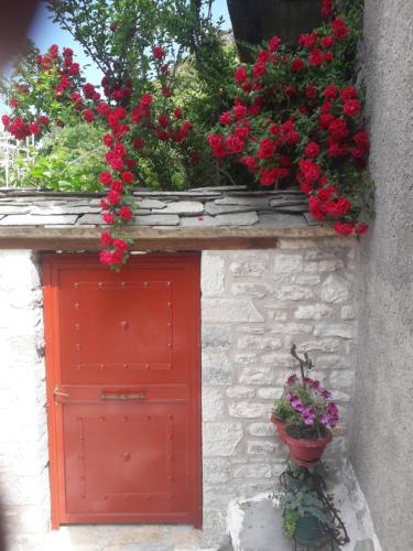 a red door with red flowers on a stone wall at Studio Penelope in Kerasochórion