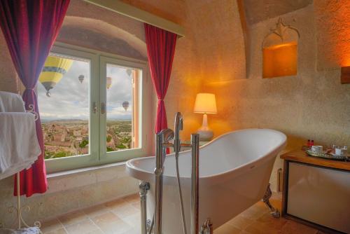 a bathroom with a tub and a large window at Takaev Cave House in Uçhisar