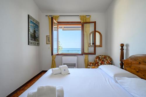 Un dormitorio con una gran cama blanca y una ventana en Casa sulla spiaggia en Cala Gonone
