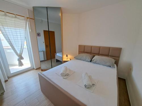 a bedroom with a large white bed with towels on it at Apartments Leticia in Baška