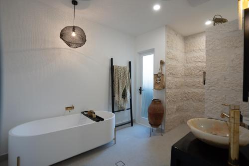 Baño blanco con bañera y lavamanos en The Manly House - 100 steps from Manly Beach en Sídney