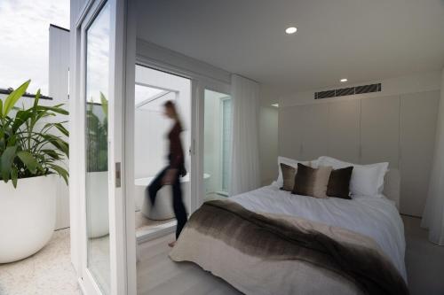 a woman is walking in a bedroom with a bed at The Manly House - 100 steps from Manly Beach in Sydney