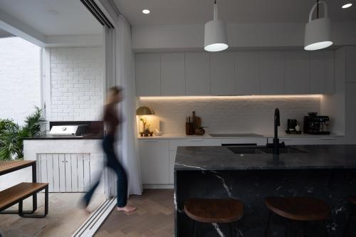a person walking in a kitchen with a counter at The Manly House - 100 steps from Manly Beach in Sydney