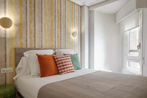 1 dormitorio con cama con almohadas y ventana en Be Bop by FeelFree Rentals, en San Sebastián