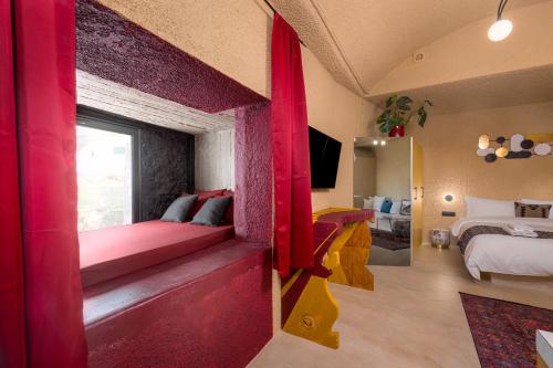 a room with red curtains and a bedroom with a bed at Canyon Santorini in Fira