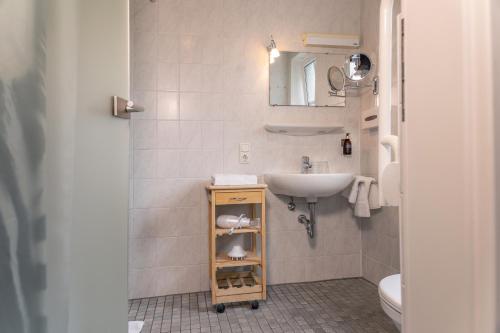 a white bathroom with a sink and a mirror at HOTEL DÜNENLÄUFER Carolinensiel in Carolinensiel