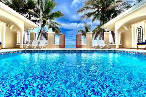 a large swimming pool with chairs and palm trees at Las Casitas of Villa Paraiso / Beachfront & Pool in Big Creek
