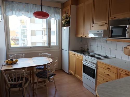 a kitchen with a table and a white refrigerator at Cozy Nest, apartement in the center of Rovaniemi in Rovaniemi