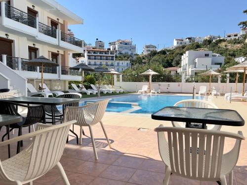 een patio met tafels en stoelen naast een zwembad bij Skiathos Somnia in Skiathos-stad