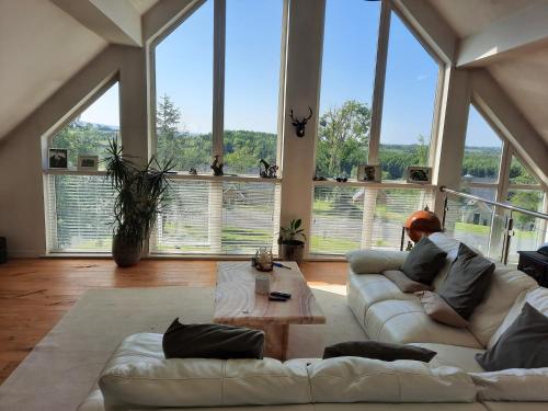 a person sitting on a couch in a living room with large windows at 3 Bed-Sleeps 6-Pets-River View-Hot Tub in Belturbet