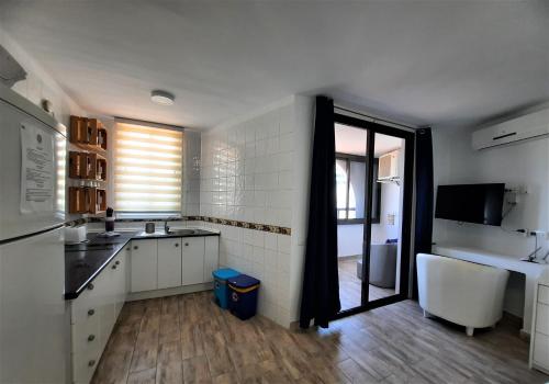 eine Küche mit weißen Schränken, einem Waschbecken und einem Fenster in der Unterkunft ZioCarlo/Las Americas in Playa de las Americas