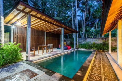 a swimming pool in a backyard with a pergola at VILLA Surya 3 rooms , waterpool, near the ocean in Candidasa