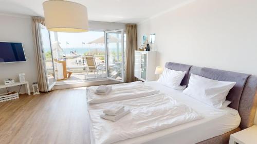 ペルツァーハケンにあるVilla Meeresrauschen Meerblick 6bのバルコニー付きの客室で、白い大型ベッド1台が備わります。