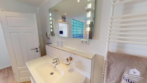 a white bathroom with a sink and a mirror at Villa Meeresrauschen Meerblick 6b in Pelzerhaken