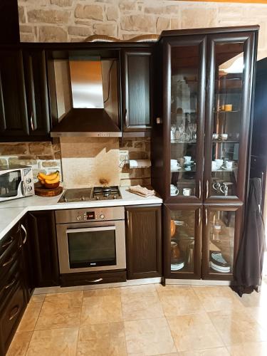 a kitchen with wooden cabinets and a stove top oven at Petrini Villa with swimming pool in Kapparianá