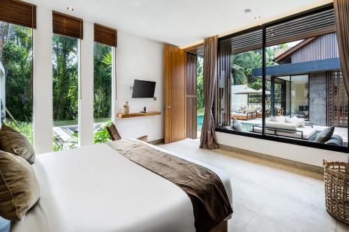 um quarto com uma cama branca e janelas grandes em Villa Leda by BaliSuperHost em Ubud