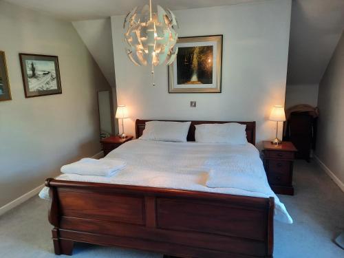 a bedroom with a large bed with white sheets and a chandelier at Stunning 55 Riverun on the banks of the lovely Riv in Belturbet