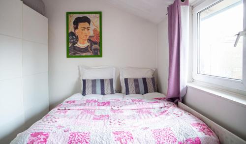 a bedroom with a bed with a pink and white comforter at Plush Stay for Four in Central Brixton in London