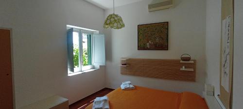 ein Schlafzimmer mit einem orangenen Bett und einem Fenster in der Unterkunft PinkSunsetRavello in Ravello