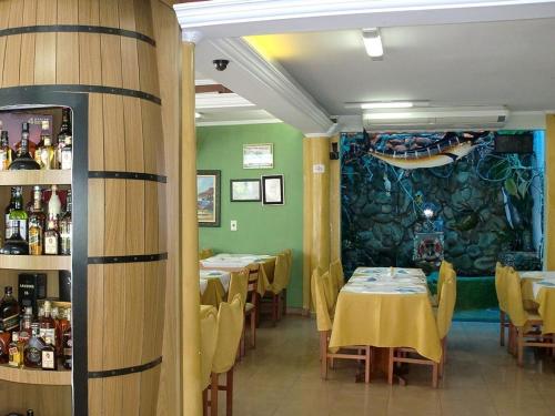 um restaurante com mesas e cadeiras e uma sala com paredes verdes em Astúrias Praia Hotel no Guarujá