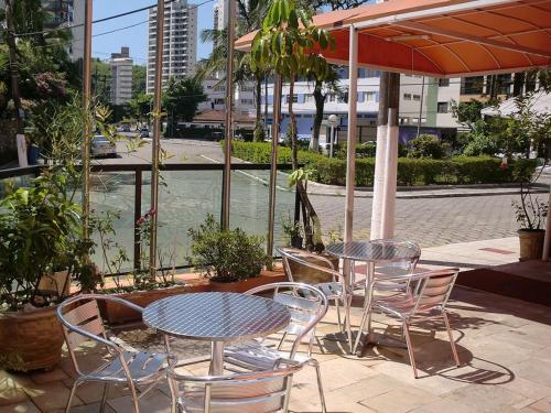 eine Terrasse mit 2 Tischen, Stühlen und einem Sonnenschirm in der Unterkunft Astúrias Praia Hotel in Guarujá