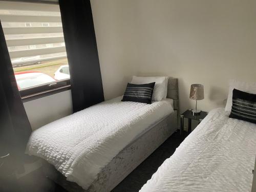 a small bedroom with two beds and a window at Argyll Apartment Loch Lomond in Balloch