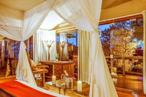 a bedroom with a canopy bed with candles on it at Mara Leisure Camp in Talek