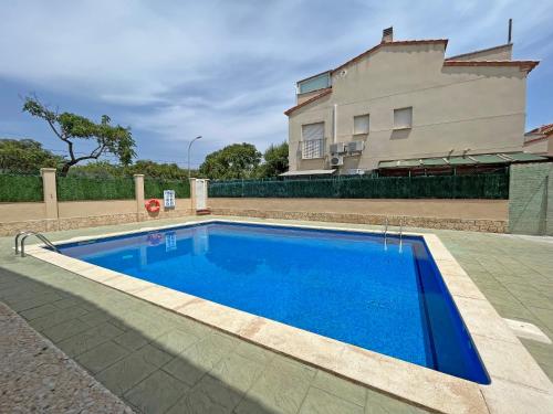 a blue swimming pool in front of a house at CASA EN VILAFORTUNY CON BARBACOA PISCINA COMUNITARIa in Cambrils