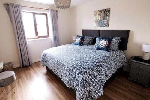 a bedroom with a bed with blue pillows and a window at Lovely two bed home in Cemaes, Anglesey in Cemaes Bay