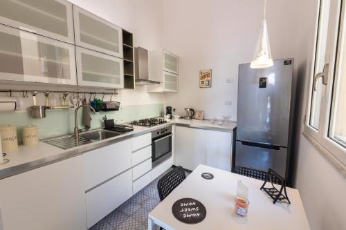 a kitchen with white cabinets and a stainless steel refrigerator at SHANTI HOLIDAY HOUSE in Palermo