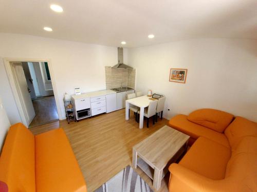 a living room with an orange couch and a kitchen at Apartments Eis in Baška