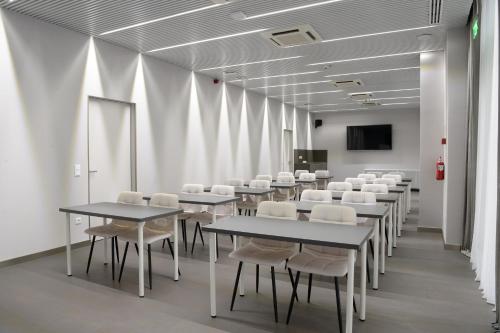 a conference room with tables and white chairs at Premier Hotel Miskolc in Miskolc
