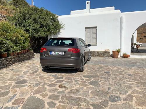 a car parked in front of a white building at Greek traditional Island Villa Sai Villa in Loutrá