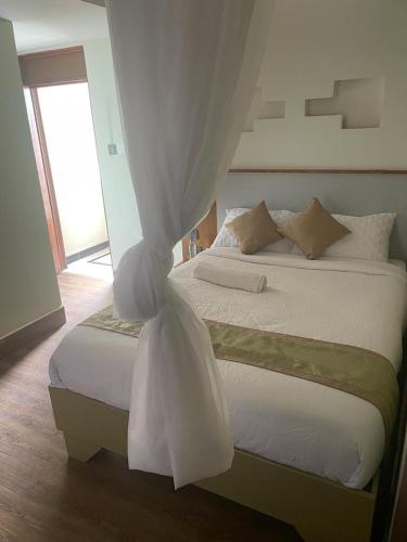 a bedroom with a bed with a white canopy at SILVER SLOPES RESORT AND SPA in Kagio