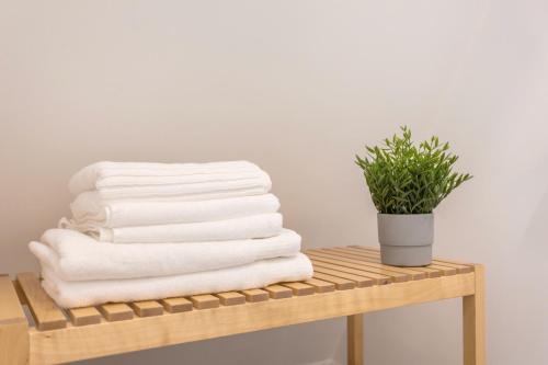 una pila di asciugamani su una mensola in legno con una pianta di Setúbal CityCenter Studios a Setúbal