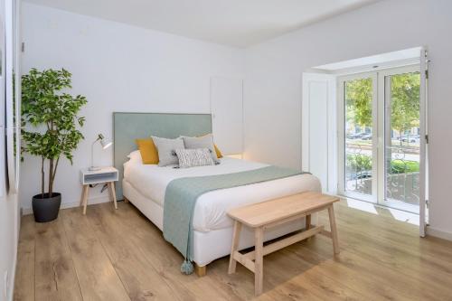 a white bedroom with a bed and a table at Setúbal CityCenter Studios in Setúbal