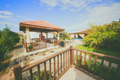 una terraza de madera con cenador y mesa en CASTLE KARPASIA Guest House, en Rizokarpaso