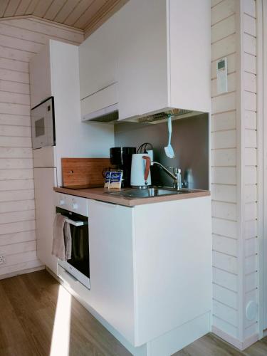 a kitchen with white cabinets and a sink at Willa Rauha 2B, minikoti, wifi, ei saunaa in Lumijoki