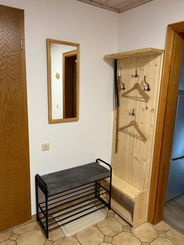 un banc dans une pièce avec une porte et un miroir dans l'établissement Haus Stiafei, à Schneizlreuth